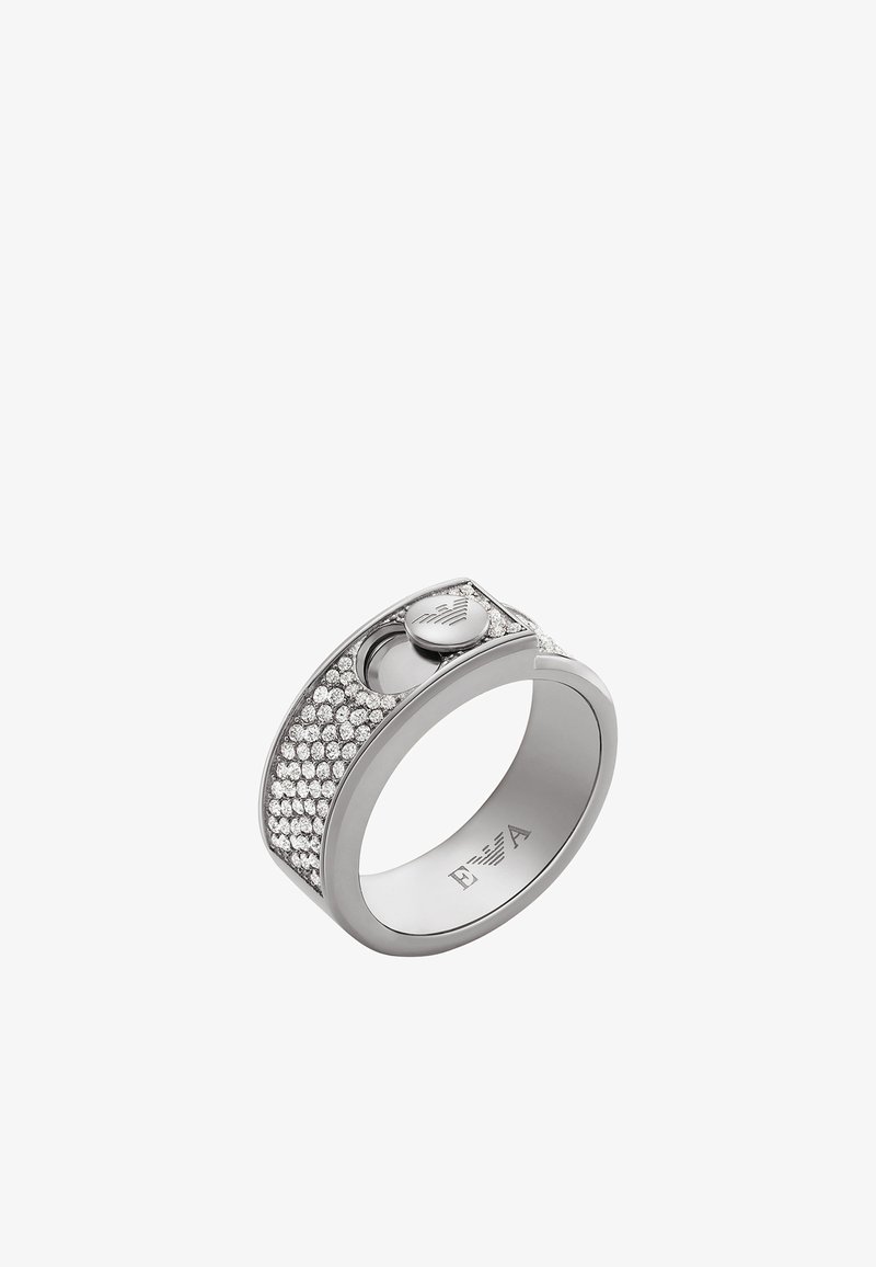 Silverring med en slät band, dekorerad med en rad klara kristaller och ett litet cirkulärt emblem på sidan.