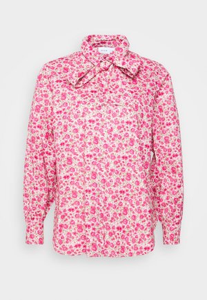 Overhemd met lange mouwen met roze bloemenpatroon en een grote strik bij de kraag, witte achtergrond.