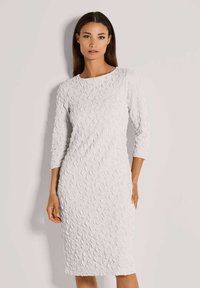 Weißes Kleid mit 3/4-Ärmeln, strukturierte Oberfläche mit blattähnlichen Mustern, taillierte Silhouette, knielanges Design, runder Ausschnitt.