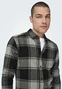 Geruite shirt in zwart en grijs flanel, met een knoopsluiting kraag en lange mouwen, met een klassiek ruitpatroon en zachte textuur.
