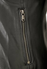 Schwarze Lederjacke mit einer Reißverschlusstasche mit metallischem Reißverschluss, glatter Textur und detaillierten Nähten entlang der Säume.