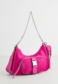 Borsa a tracolla in nylon rosa con una catena argentata, dotata di una tasca frontale con zip, dettaglio fibbia e accenti texturizzati sulla tracolla.