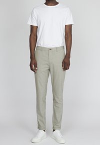 Ljust grå, randiga byxor med skräddarsydd passform, med knappstängning och sidofickor, i kombination med en enkel vit t-shirt och vita sneakers.