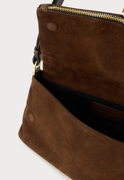 Braune Wildleder-Handtasche mit Reißverschluss und goldfarbenen Beschlägen. Innenfach mit schwarzer Innenauskleidung sichtbar. Weiche Textur und abgerundete Form.