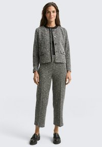 Op maat gemaakte grijs-zwarte pied-de-poule jas met knoopsluiting, gecombineerd met bijpassende cropped broek. Soepele textuur, standaard pasvorm en zijzakken.