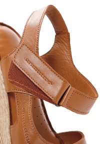 Sandalo in pelle marrone con cinturino testurizzato, fibbia regolabile e design aperto. Presenta perforazioni per la traspirabilità e dettagli intrecciati.