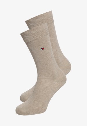 Beige bomuldsstrømper med ribbet tekstur, der har et lille rødt, hvidt og blåt logo på siden. Standard crew-længde design.