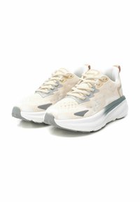 Zapatillas de correr beige claro con parte superior de malla que presenta un diseño texturizado, acentos grises y una suela blanca acolchada.