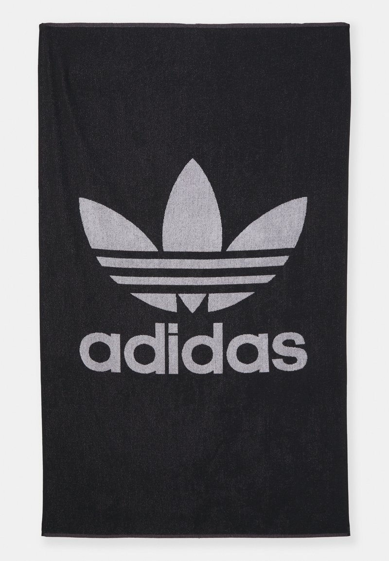 Toalla de algodón negra con un gran logo trefoil gris de Adidas y la palabra "adidas" en letras gruesas. Textura suave con un patrón uniforme.