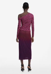 Yksihihainen vaaleanpunainen paita, jossa on ruutukuosi, yhdistettynä liukuväriseen mauvehameeseen. Mallilla on mustat remmikengät. Sileä pinta.