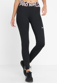 Leggings de sport noirs avec une taille haute, ornés du texte rose "PRO NIKE", fabriqués dans un tissu extensible, conçus pour le confort et la mobilité.