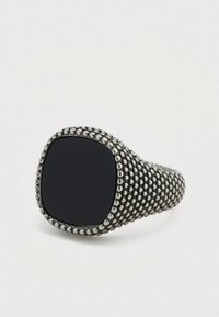 Δαχτυλίδι από μαύρη πέτρα με τετράγωνο πρόσωπο, διακοσμημένο με μια υφή ασημένιας μεταλλικής ταινίας που διαθέτει στρογγυλεμένες λεπτομέρειες σαν χάντρες γύρω από τις άκρες.