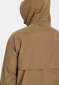 Veste de pluie marron à capuche avec cordon réglable sur la capuche, coutures verticales et soufflet au dos, vue de dos.