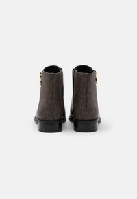 Bottines marron avec un motif texturé, des accents noirs, des fermetures éclair sur les côtés et un talon bas et robuste. Présente des éléments en métal doré sur la fermeture éclair.