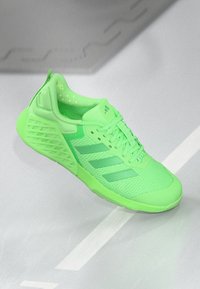 Chaussure de sport verte fluo avec une tige en mesh respirant, trois bandes horizontales, semelle extérieure texturée et col rembourré.