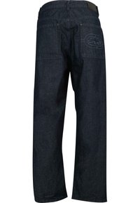 Mørkeblå denimbukser med avslappet passform, med to baklommer og et distinkt sømdesign nær høyre lomme.