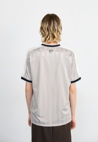 Light gray short-sleeve jersey with vertical stripes, black collar and cuffs, and a logo on the upper back. Smooth fabric texture.