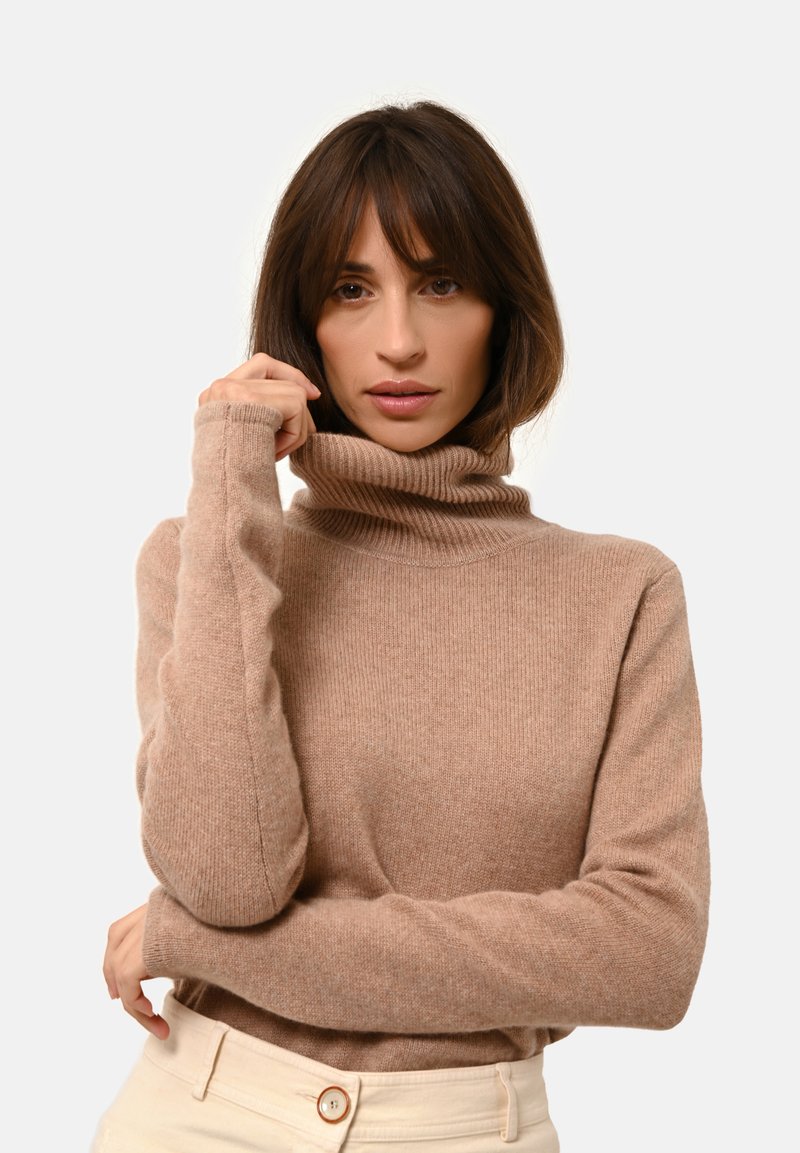 Pull col roulé beige avec texture côtelée, doté de manches longues et d'un design ajusté. Tissu lisse avec un subtil éclat.
