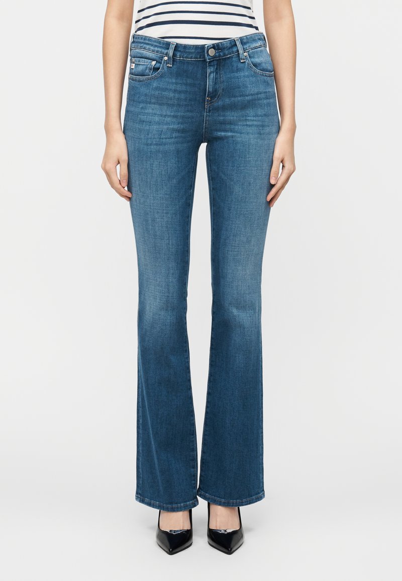 Μπλε τζιν παντελόνι με ελαφρώς φαρδύ καμπάνα, μεσαία μέση, σχεδίαση με πέντε τσέπες και διακριτική ξεθώριαση. Το υλικό έχει απαλή υφή.