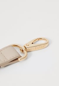 Portachiavi in pelle beige di Valentino con cinturino e moschettone in metallo dorato, caratterizzato da un marchio inciso. Texture liscia e costruzione robusta.