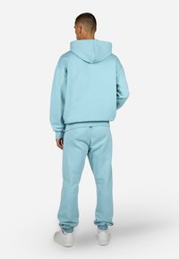 Set di felpa e pantaloni jogger in morbido tessuto blu chiaro. La felpa con cappuccio presenta una tasca a marsupio, polsini a coste e una cintura elastica.