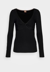 Czarny top z długim rękawem wykonany z prążkowanej tkaniny, z głębokim dekoltem w kształcie litery V i wiązaniem na środku przodu. Dopasowany fason.