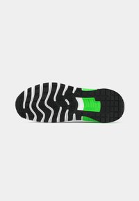 Black and white sneaker sole with green accent. Features textured rubber for grip, molded patterns for flexibility, and a cushioned midsole.