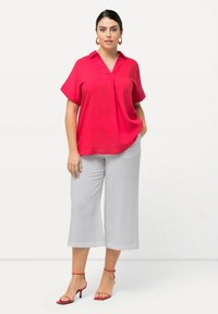 Felrood kortoevenshirts met een kraag, gecombineerd met lichtgrijze wijde broek en rode sandaaltjes met straps. Eenvoudig, textuur ontwerp van de stof.
