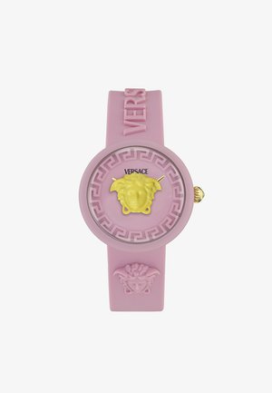 Rozā gumijas pulkstenis ar apaļu seju, uz kuras attēlota dzeltena Medūzas dizaina, zelta rādītājiem un Grieķu atslēgas ornamentiem, ar "VERSACE" zīmolu.