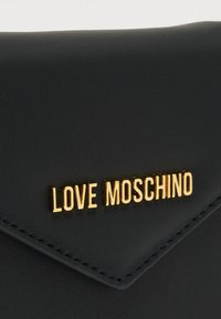 Μαύρο δερμάτινο πορτοφόλι με υφή, με χρυσό λογότυπο "LOVE MOSCHINO" εμφανισμένο στη μπροστινή πλευρά και σχεδιασμό τριγωνικής κλείστρας.