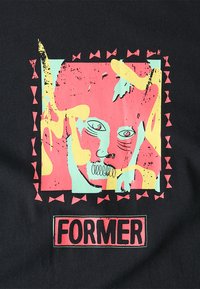 Fekete szövet póló színes grafikai dizájnnal, pink, menta zöld és sárga árnyalatokkal, háromszögmintákkal körülvéve, valamint a "FORMER" felirattal vastag betűkkel.