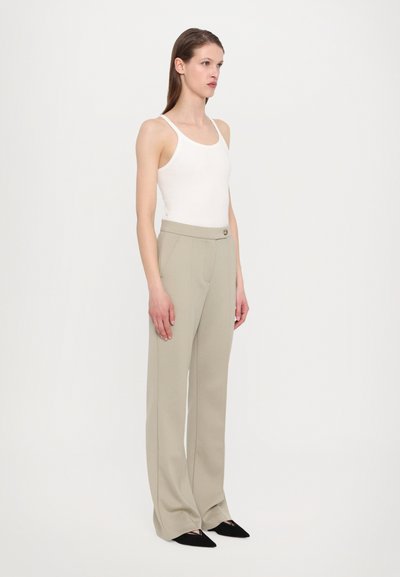 Gai pelēki piegriezti bikses ar gludu tekstūru, sānu kabatām un vienu pogu, kombinētas ar pieguļošu baltu bezmaku.