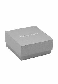 Scatola regalo in cartone grigio con finitura testurizzata. Il coperchio presenta lettere bianche che formano la scritta "MICHAEL KORS". Forma quadrata con una chiusura sicura.