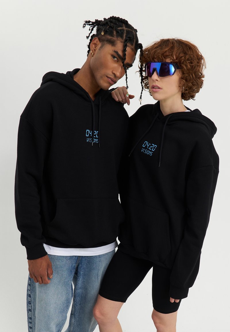 Black hoodies with a front pocket, featuring blue text "04:20 VISIONS." One individual wears sunglasses, paired with light denim and black shorts.