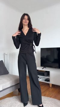 Fekete átkötős felső V-nyakkivágással és oldalt megkötővel, magas derekú, bő szárú fekete nadrággal párosítva. Simaságot sugárzó anyag és elegáns kialakítás.