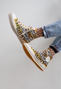 Höga sneakers med en vit gummisula, med ett grafiskt mönster i gult, svart och vitt. Tillverkade av canvasmaterial och med snörningsdesign.