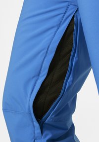 Modré sportovní kalhoty s větráním ze síťoviny na zip. Tkanina vypadá hladce s mírným leskem, což zvýrazňuje přizpůsobený tvar a design.