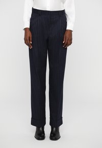 Navy trousers with pinstripes, featuring a pleated front, cuffed hems, and a smooth, textured finish. Worn with a white button-up shirt.