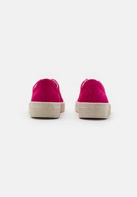 Rosa Wildleder-Sneaker mit einer strukturierten beigen Gummisohle, die ein rundes Design und subtile Nähtetails auf der Rückseite aufweisen.