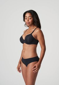 Czarny komplet biustonosza i majtek wykonany z gładkiego materiału. Biustonosz ma miękkie miseczki i regulowane ramiączka; majtki mają niską talię.