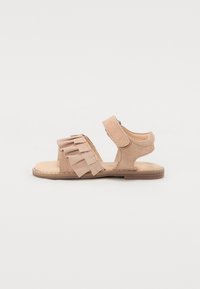 Tan mockasinsandaler med justerbar rem, vågig detalj framtill, öppen tådesign, platt sula och stickade kanter.