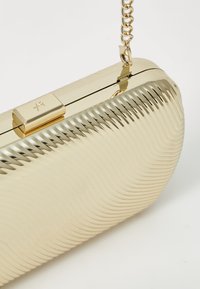 Gold metallic clutch bag with a ribbed texture, rectangular shape, and a chain strap. Features a secure clasp closure.