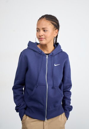 Navy blue zip-up hoodie made from soft material, featuring a drawstring hood, kangaroo pockets, and a white Nike logo on the chest.