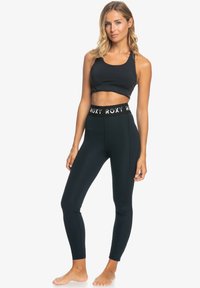 Top sportivo nero e leggings a vita alta con il marchio Roxy; design aderente, tessuto elastico, texture liscia e lunghezza alla caviglia.