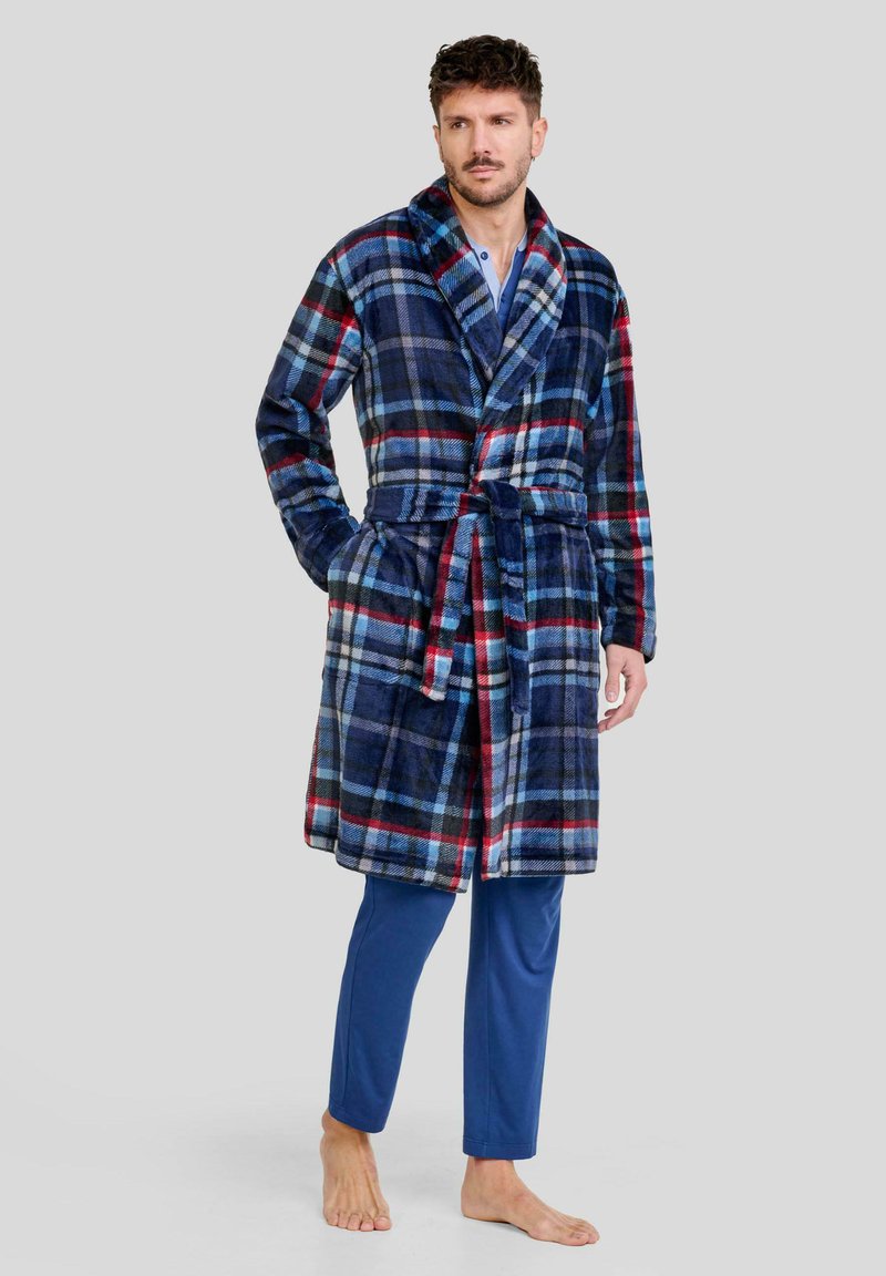 Bata de felpa azul marino con un patrón de cuadros en rojo y azul claro; presenta un cuello chal, cinturón de lazo y bolsillos laterales. Lleva puesta sobre pantalones azules.