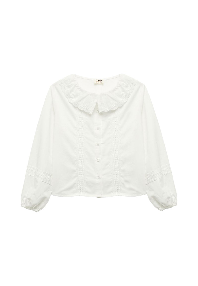 Hvid bluse med flæsekrave, lange pufærmer og lukning med knapper foran. Har lace-detaljer langs brystet og ærmerne.