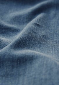 Jeans tyg i en djupblå nyans, med en mjuk textur och synlig vävstruktur samt subtila färgvariationer.