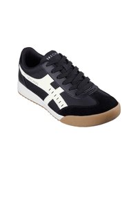 Zapatilla en blanco y negro con una parte superior de ante y sintética, que presenta una suela de goma, cordones texturizados y franjas laterales prominentes.