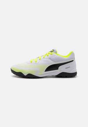 Scarpa sportiva bianca con una parte superiore testurizzata, lacci giallo neon e dettagli neri. Presenta un design leggero e una suola in gomma resistente.