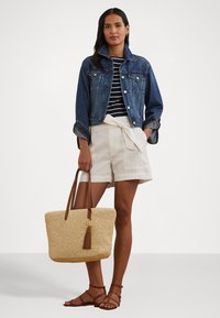 Τζάκετ από τζιν, ριγέ τοπ, λευκές σορτς ψηλής μέσης με φιόγκο, καλαθάκι από ψάθα με δερμάτινες λαβές και φούντα, καφέ σανδάλια με λουριά.